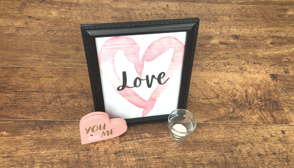 Love sign framed in a black frame beside a heart and a candle