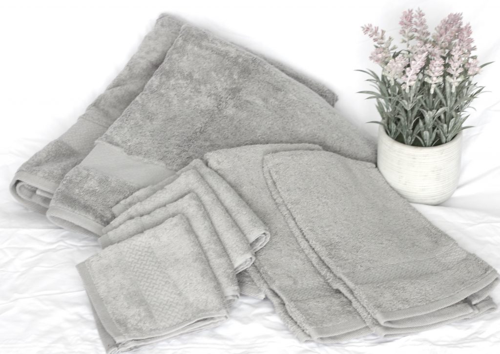 Set of grey towels for guests beside lavender flowers