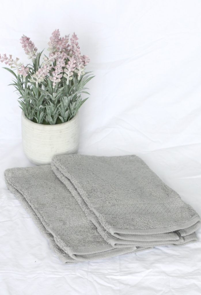Two grey towels beside lavender pot.