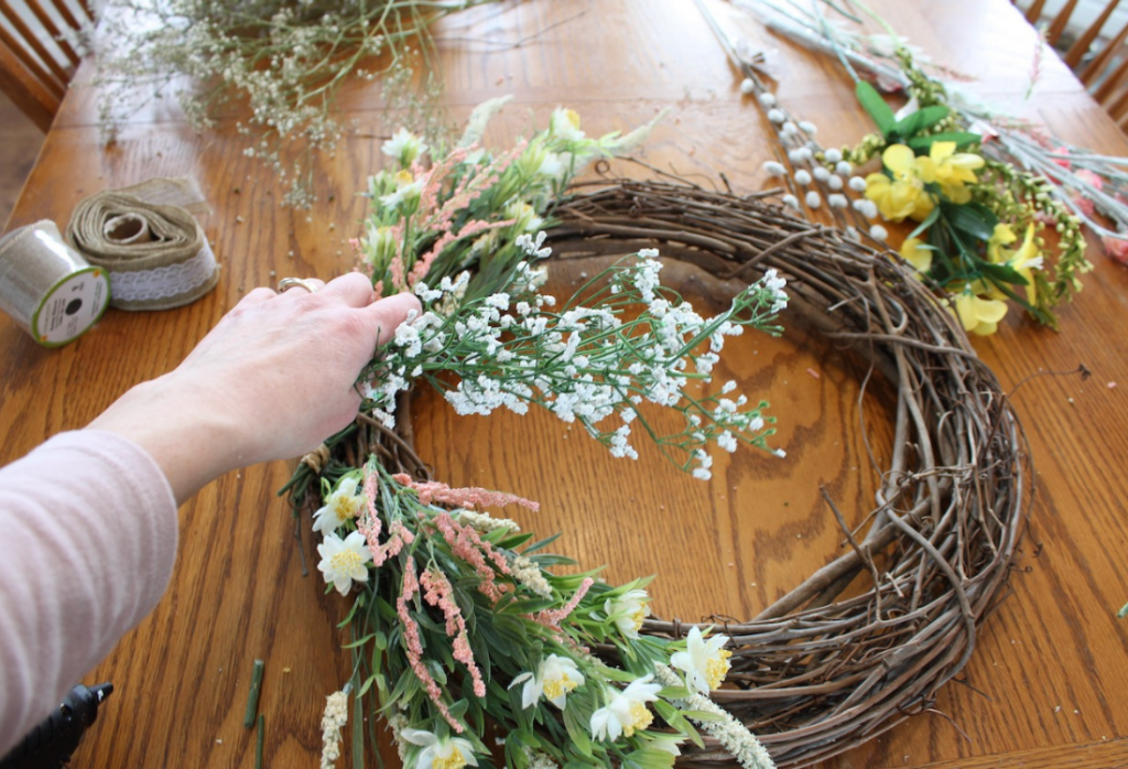 Wreath in the background with a hand showing babies breath florals