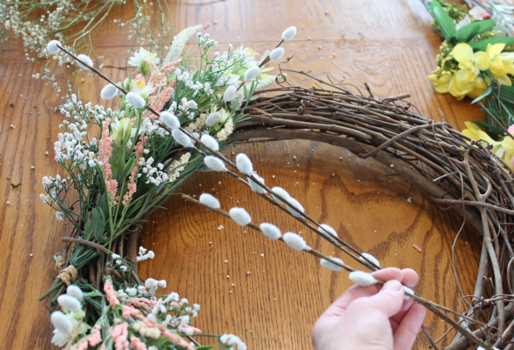 Wreath on the background with a hand showing pussy willow stems