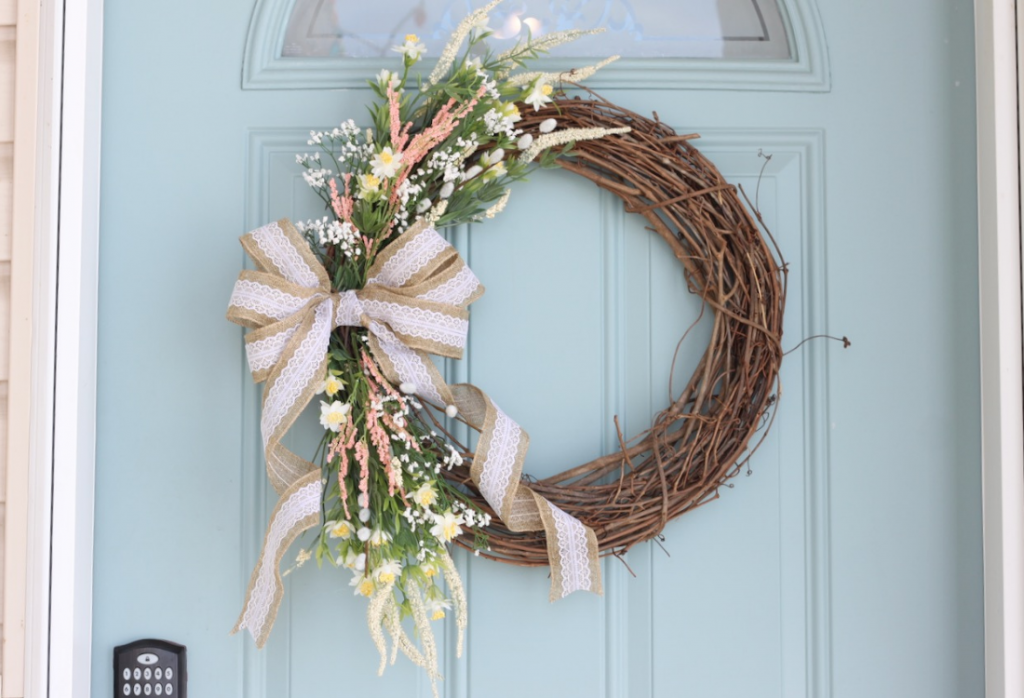 Close up of of a spring wreath hanging on a blue door