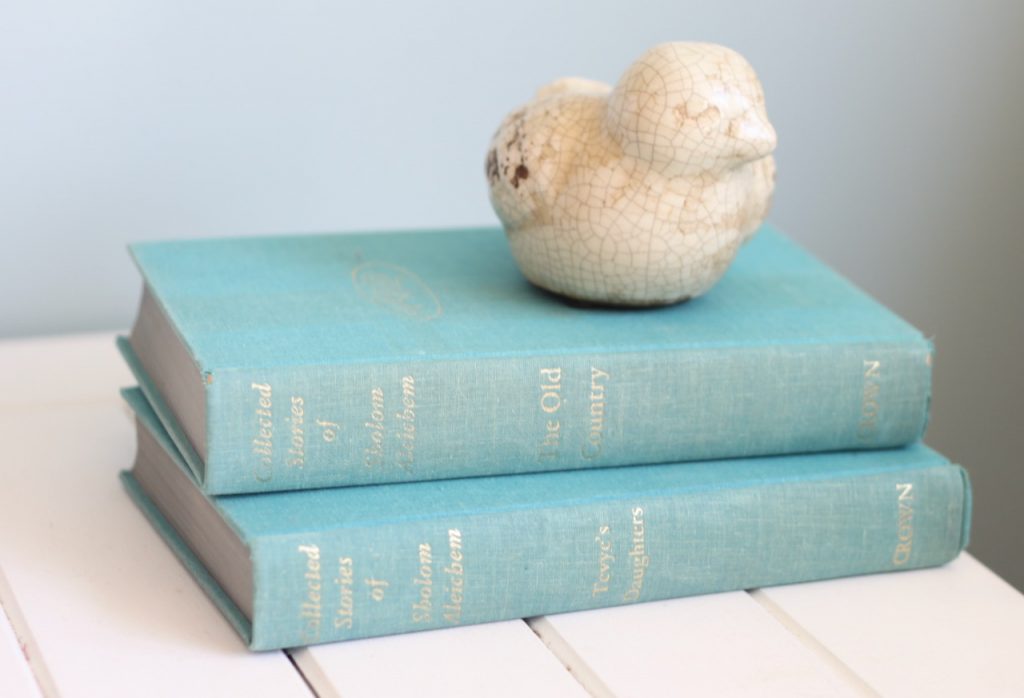 Two aqua thrifted books on white table with cream bird on top