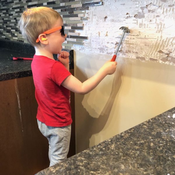 kid in red shirt hammering on wall during home renovation