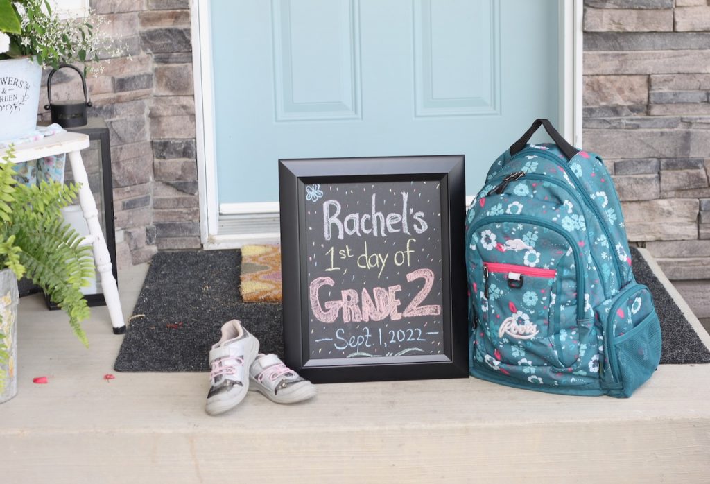 School sign with backpack and shoes on front step